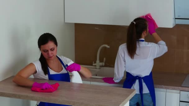 Dos chicas morenas se dedican a limpiar y hablar entre ellas. Guantes rosados para limpiar. — Vídeos de Stock