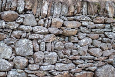 Taş bir duvara yığılmış bir sürü gri eski taş. Taşların bariyeri