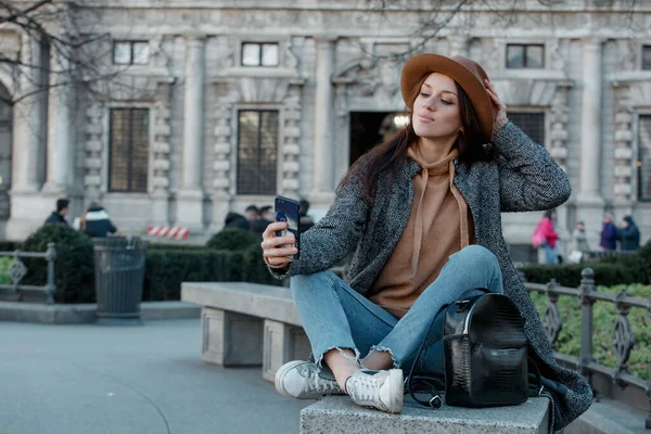 Menina colocando a mão em um chapéu marrom na moda e tirar uma selfie . — Fotografia de Stock