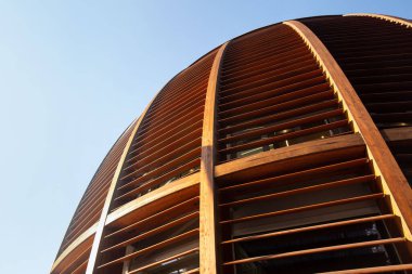 Mavi gökyüzüne karşı yatay çizgileri olan yarı dairesel ahşap bir kubbe. 01.2020 Milano