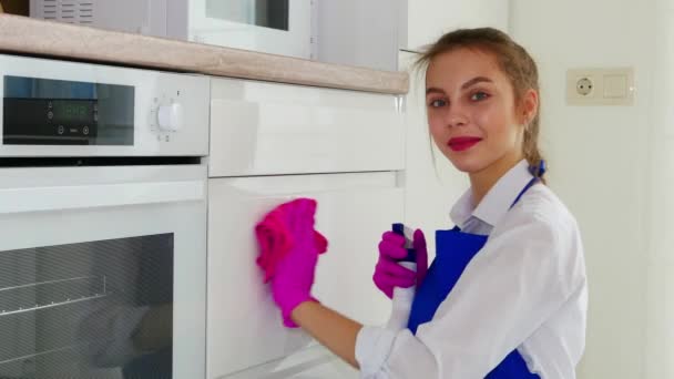 Cleaning the room, wipe the white surface with pink gloves and a pink rag. A girl with lipstick makes cleaning and looks at the camera. — Stock Video