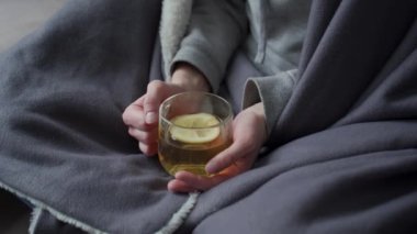 Karantina altındaki kız elinde limonlu bir fincan yeşil çay tutuyor. Limonlu sıcak çay ile servis edilir. Doğal vitamin alıyorum. Akut solunum enfeksiyonları, soğuk algınlığı ve grip tedavisi