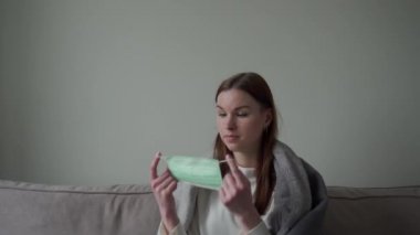 Güzel bir genç kız özel olarak nasıl tıbbi maske takılacağını gösterir. Orvi, koronovirüs, grip, akut solunum hastalığı.