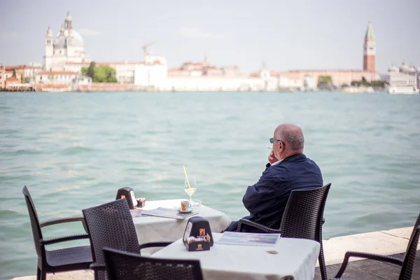 Een man drinkt een cocktail in een restaurant en kijkt naar de baai. — Stockfoto