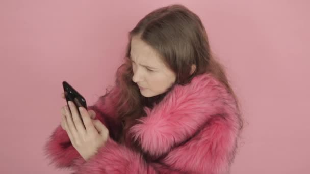 Young beautiful girl reads jokes on the Internet and answers messages on a black mobile phone. — Stock Video