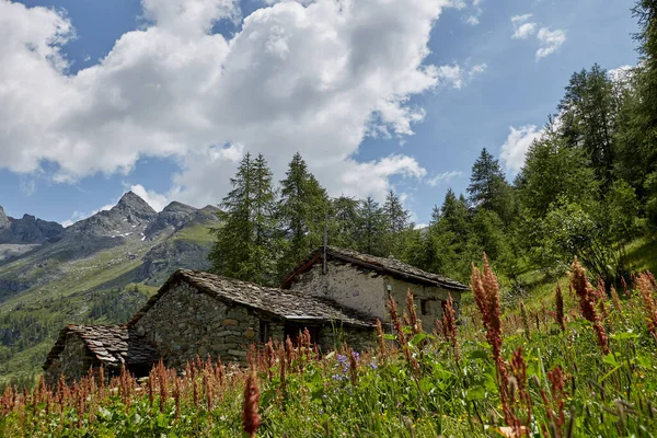 A lonely old building made of stone on a high, steep hill. Against the background of blue sky and mountains.