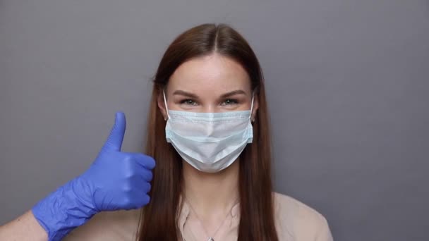 Mulher em máscara protetora mostra como sinal — Vídeo de Stock