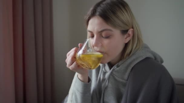The quarantined girl is treated with hot tasty tea with lemon. Getting natural vitamin. Treatment for acute respiratory infections, colds, flu, bronchitis. — Stock Video