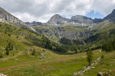 Lowland, küçük yalnız evleri olan bir yamaç. Köy evleri. Arka planda yüksek dağlar ve mavi gökyüzü var..