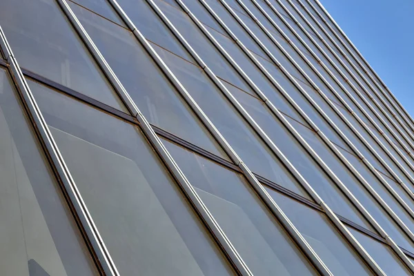 Gros plan de nombreuses fenêtres d'un immeuble de grande hauteur avec des bandes de séparation verticales. contre le ciel bleu . — Photo