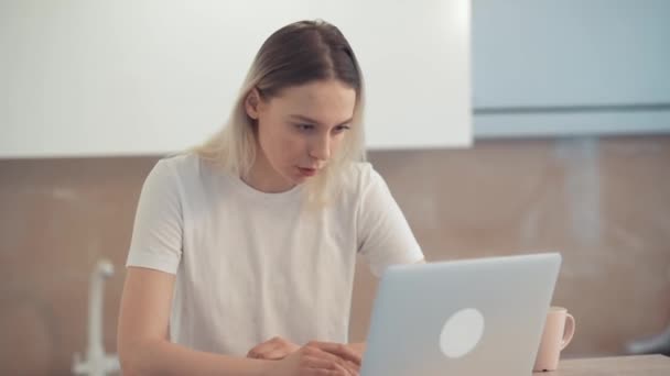 女の子はノートパソコンで情報を勉強しているし、スマートフォンに気を取られていません. — ストック動画