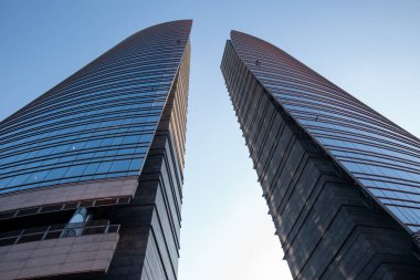 Mavi gökyüzüne karşı megalopolis yakınlarında duran iki mavi ve gri gökdelen. Milan 01.20.