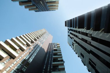 Çok sayıda pencere var. Mavi gökyüzüne karşı balkonları olan üç çok katlı fütüristik binaya bakmak. 01.20 Milano.