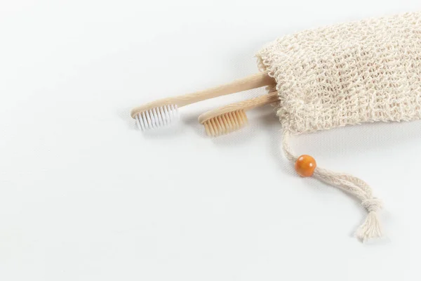 Dos cepillos de dientes hechos de madera natural, uno para el adulto y el otro para el niño en una bolsa de material natural. sobre fondo blanco — Foto de Stock