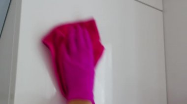 Odayı temizlemek, beyaz yüzeyi pembe eldivenler ve pembe bir bezle silmek..