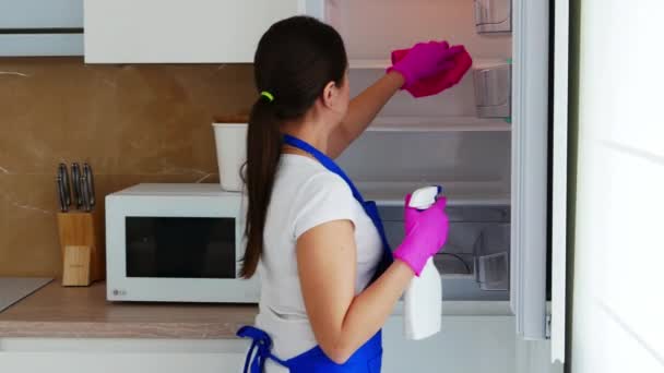 若い美しい女性は彼女の背中に立って、白い冷蔵庫を開き、棚を洗う. — ストック動画