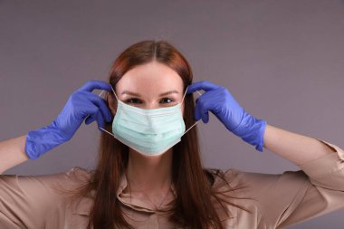Kadın Covid-19 'u korumak için nasıl cerrahi maske takılacağını öğretiyor (koronavirüs)