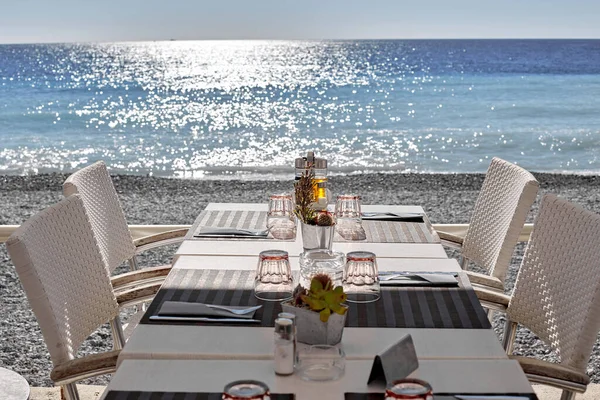 Mesa de luz para algumas pessoas em repouso. cadeiras de vime. Costa do mar azul com reflexo solar nas ondas . — Fotografia de Stock