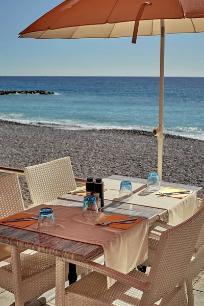 Uma pequena mesa aconchegante ao sol ao lado do mar calmo . — Fotografia de Stock
