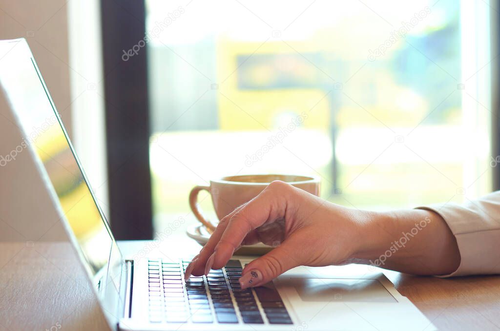 Female young hands with a long manicure work and type on the laptop keyboard.