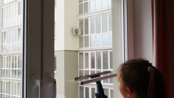 Schöne junge brünette Mädchen stehen mit dem Rücken und putzen. Das Mädchen wäscht ein Fenster mit einer speziellen Bürste zum Fensterputzen. — Stockvideo