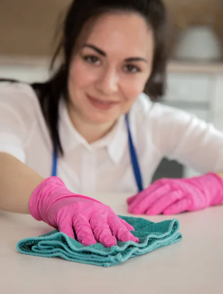 Close-up van een brunette die de keuken schoonmaakt en glimlachend naar de camera kijkt. Schoonmaken met plezier. Verticale foto — Stockfoto