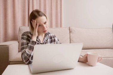 Genç güzel kız dizüstü bilgisayarla zor bir iş yapıyor. Kız başını sıkıca tutuyor..