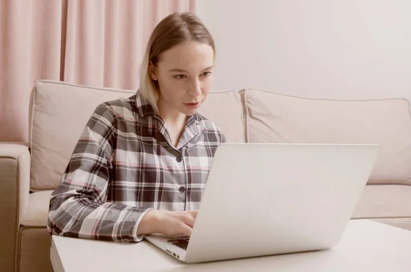 Fiatal gyönyörű lány koncentrált és komolyan tanul online előtt egy fehér laptop. — Stock Fotó
