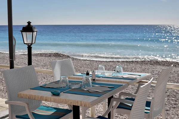 Linda mesa branca com uma toalha de mesa azul na praia . — Fotografia de Stock