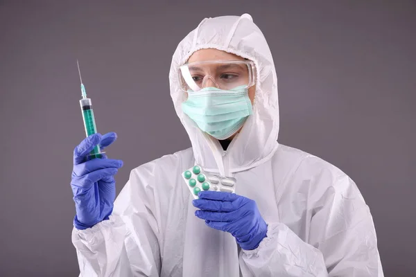 Woman in protective wear looks on pills