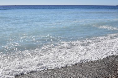 Küçük deniz dalgaları üzerinde beyaz deniz köpüğü. Ufuk çizgisi.