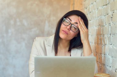 Baş ağrısı, yorgunluk, genç ve güzel bir kız öğrencinin dizüstü bilgisayarla internetten çalışması..