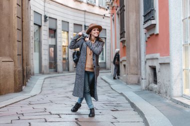 Küçük bir sokakta elinde kamerayla gezen güzel bir turist..