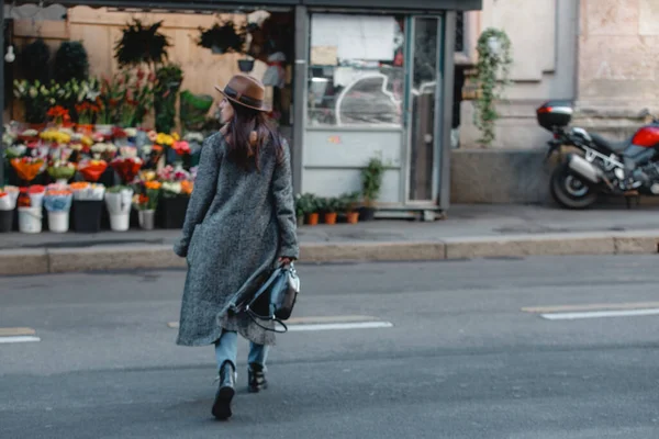 Jovem bela menina turista cruza a estrada contra o fundo de uma loja com buquês brilhantes e flores . — Fotografia de Stock