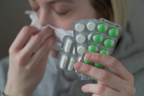 sick womanwhith runny nose shows pills to camera