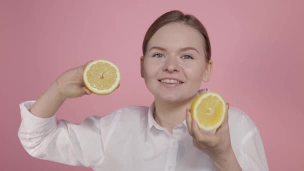 Una joven sostiene en sus manos dos grandes rodajas amarillas de limón — Vídeos de Stock