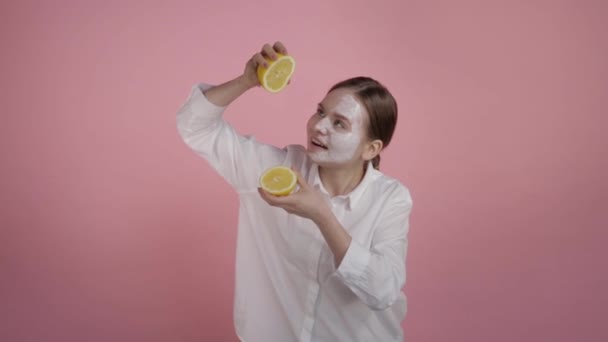 Girl squeezes juice from a lemon. On a pink background. — Stock Video