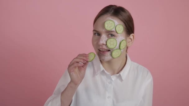 Giovane ragazza della pelle. Maschera naturale con crema e fette di cetrioli . — Video Stock