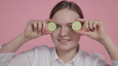 Genç bir kız iki büyük limon dilimini elinde tutuyor, suyu sıkıyor ve suyun nasıl aktığına bakıyor..