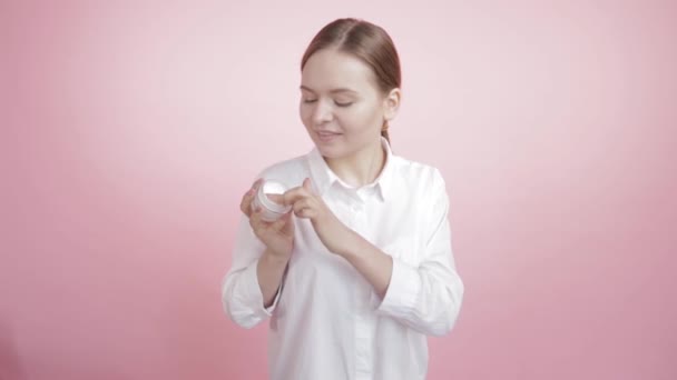 Mooi meisje met natuurlijke schoonheid zet witte crème op haar gezicht en wang. — Stockvideo