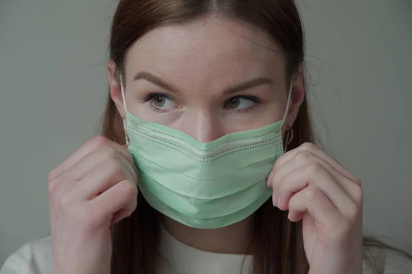 医者のマスクに長い赤い髪の美しい若い女の子のクローズアップ.Orvi,コロノウイルス,急性呼吸器感染症. — ストック写真