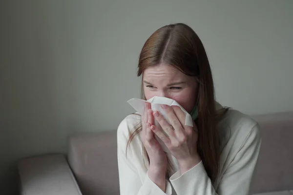 Una joven se enferma y se sopla la nariz con una toalla blanca desechable . — Foto de Stock