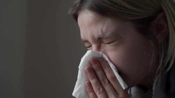 A menina loira senta-se com os olhos fechados, tem doenças virais e sopra o nariz. Sintoma de Orvi, coronovírus, gripe, doença respiratória aguda, alergia, sinusite . — Vídeo de Stock