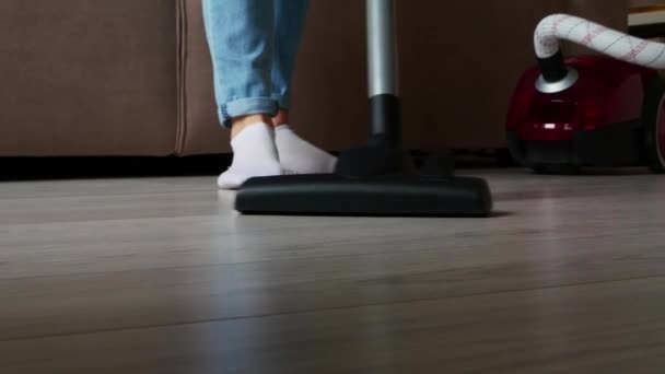 Close-up dipotong gambar seorang gadis yang melakukan pembersihan, menyedot lantai dengan vacuum cleaner merah — Stok Video