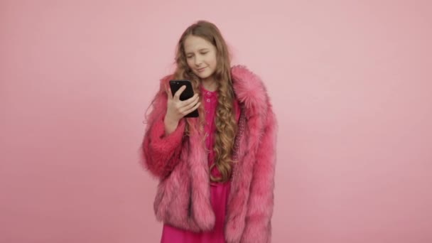 A young girl in a pink coat is holding a phone that has stopped working. — Stock Video