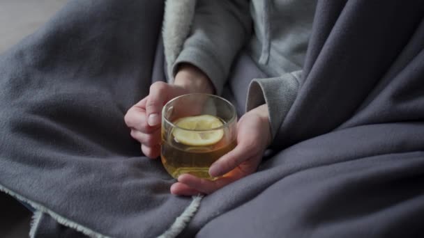 La chica en cuarentena sostiene una taza de té verde con limón en las manos. Tratada con té caliente sabroso con limón . — Vídeo de stock