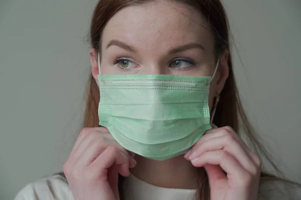 医者のマスクに長い赤い髪の美しい若い女の子のクローズアップ.Orvi,コロノウイルス,インフルエンザ,急性呼吸器感染症. — ストック写真