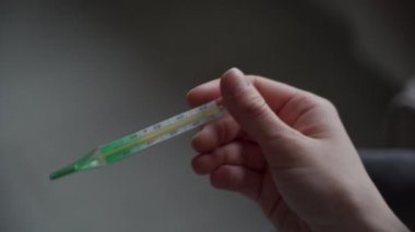 Karantina altındaki kız cıva termometrenin sıcaklığının yükselip yükselmediğini kontrol ediyor. Orvi belirtisi, koronovirüs, akut solunum hastalığı..