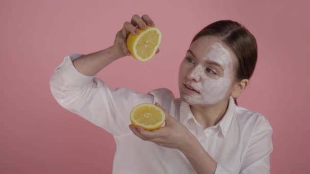Een meisje met natuurlijke schoonheid en zonder make-up perst sap uit een citroen. — Stockvideo