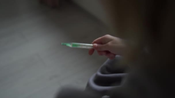 Dívka zabalená do přikrývky jí kontroluje teplotu. Teplotní příznaky koronoviru, chřipky, akutního respiračního onemocnění. — Stock video